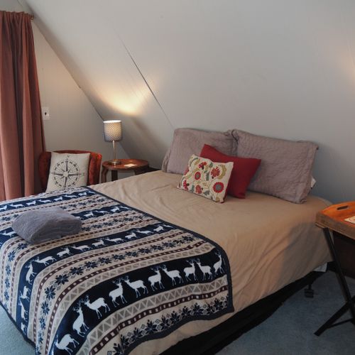 Bedroom #3 (second floor):  features a queen-size bed, walk-out balcony with lakeview, chair, nightstands with lamps, ceiling fan, and a closet.