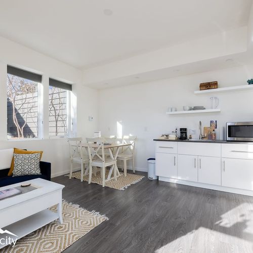 - sleek white kitchenette stocked with essentials for morning coffee or light bites
- open shelving and minimal decor keep the space fresh, functional, and inviting
- dining area with seating for four is ideal for meals, games, or remote work session