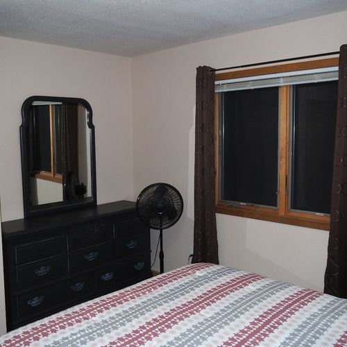 Bedroom #1 (main floor):  features a queen-size bed, nightstands, dresser, mirror, pedestal fan, and closet.