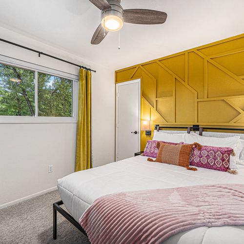 Bedroom 4 features a comfortable queen-size bed set against a striking yellow accent wall, adding a vibrant touch to the cozy space.