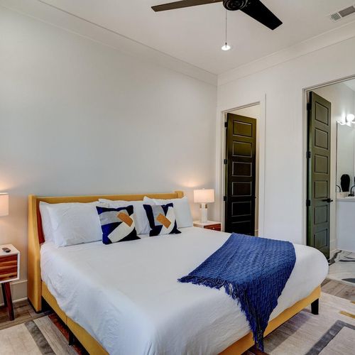 Serene first-floor bedroom w/ a cozy bed, blue accents & backyard views.