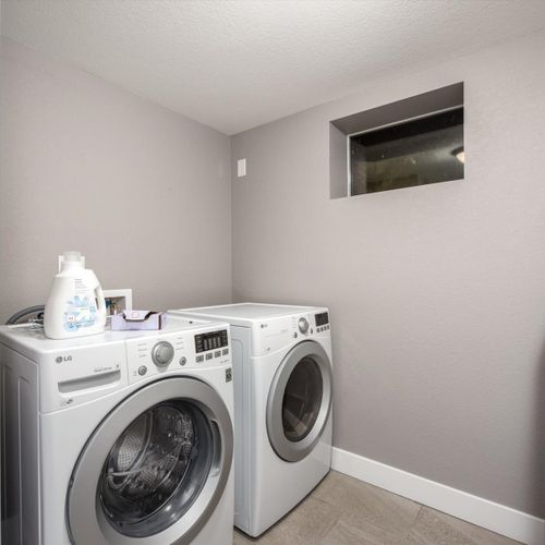 The stocked laundry room provides detergent, dryer sheets, an iron & ironing board