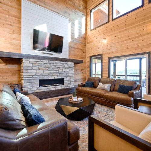 The living room has lounge seating around the stone fireplace.