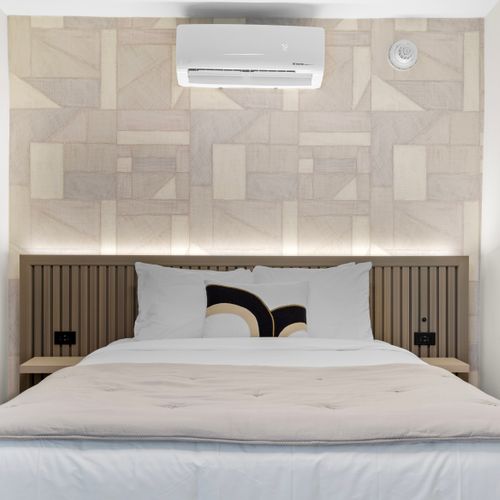The room features a unique geometric wall design and a modern air conditioning unit.