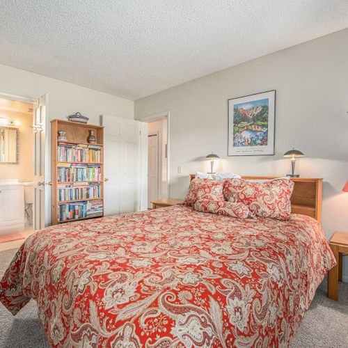 Elegant bedroom featuring ensuite bath and a built-in library filled with handpicked reads.
