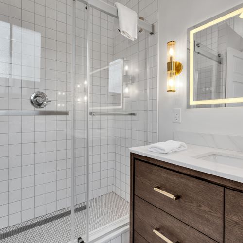 Sleek walk-in shower w/ floor-to-ceiling modern tile.