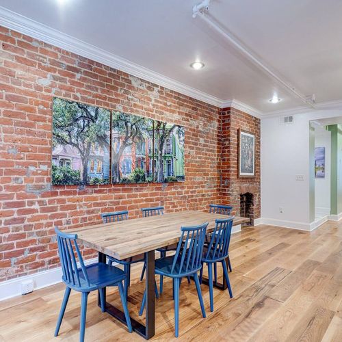 Dining space w/ seating for six, surrounded by warm exposed brick.