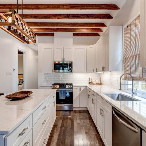 Clean white kitchen w/ exposed beams & modern fixtures for a polished, airy feel.