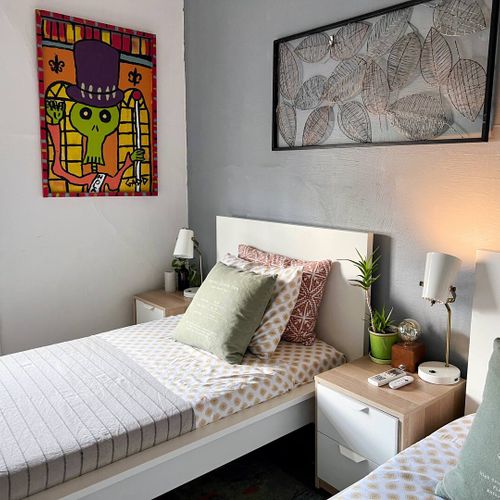 Warm bedroom w/ cozy bedding & lively wall art for a personalized touch.