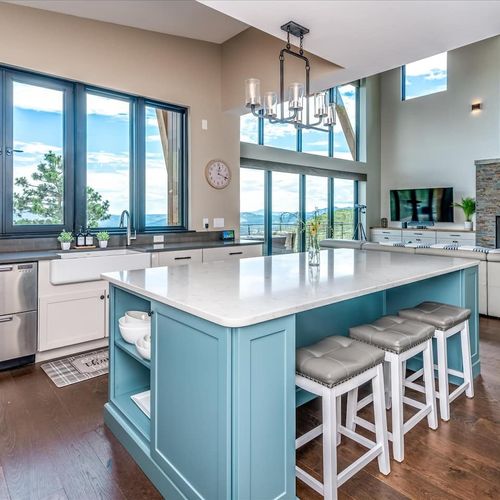 - spacious kitchen island offers ample prep space, seating, and scenic sightlines
- soft blue tones, elegant lighting, and four stools create a perfect social hub
- ideal for morning breakfasts, casual dining, or evening drinks with a view