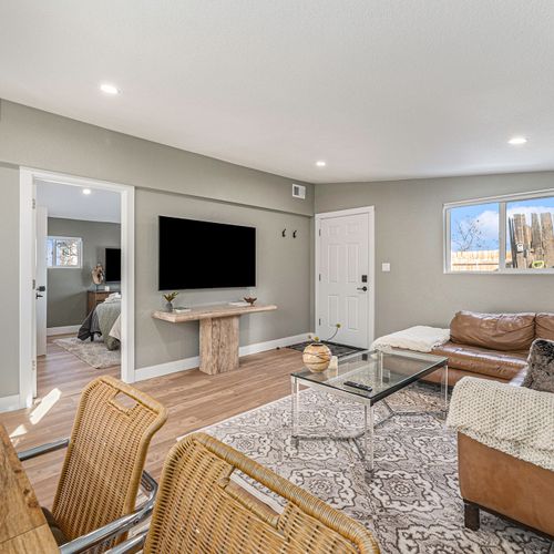 - relax with a movie night on the mounted flat screen in a warm and inviting space
- earth toned decor, natural textures, and a soft rug create a welcoming ambiance
- enjoy seamless access to the bedroom, entryway, and cozy sectional seating