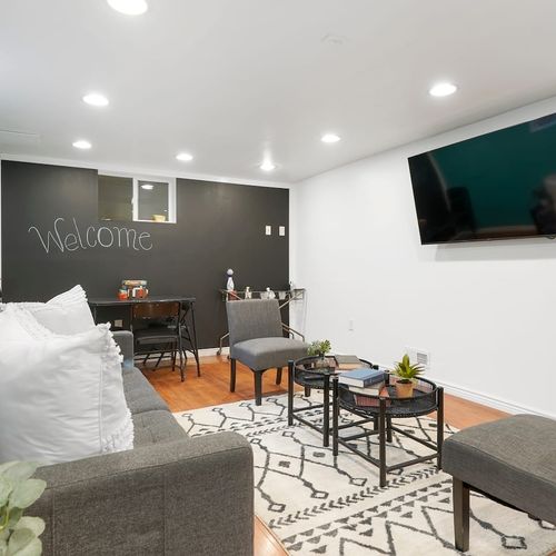 - catch a movie on the wall mounted tv or set up a game night under soft lights
- chalkboard wall adds fun, letting guests doodle, write notes, or say hi
- stylish balance of playfulness and comfort in this well lit basement