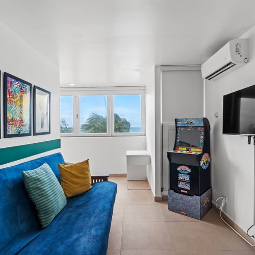 Chill out and enjoy the ocean views from our vibrant living room, complete with a classic arcade game for endless entertainment.
