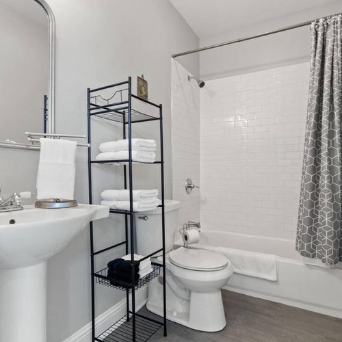 Well-organized bathroom w/ a tub/shower combo & open shelving.