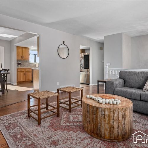 - open layout seamlessly connects the living room to kitchen and hallway for easy flow
- neutral walls and wood flooring create a warm, cohesive base throughout the home
- ideal for hosting, relaxing, or watching a movie on the cozy gray sectional