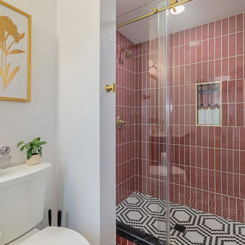 This eclectically-styled bathroom features a glass-enclosed shower, beautiful brass accents and ornate tiles from floor to ceiling.