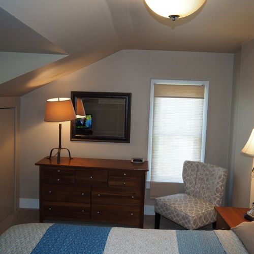 Bedroom #1:  features a queen-size bed, mirror, nightstands, lamps, dresser, chair, and television.