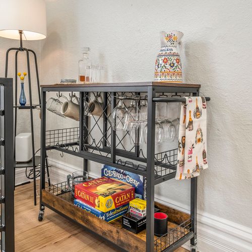 Entertain in style with our chic bar cart, stocked and ready for fun! Board games add a playful touch to the inviting dining area.