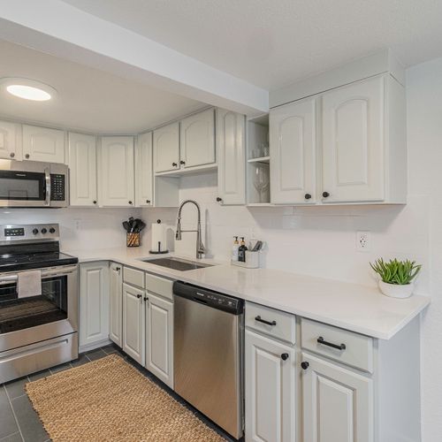 - prepare meals with ease in a fully stocked kitchen with stainless steel appliances
- timeless white cabinetry and soft tile flooring give the space a welcoming feel
- touch of greenery and simple decor keep the vibe fresh and functional