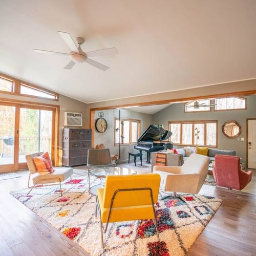 Open concept living room area with sectional, smart TV and grand piano.