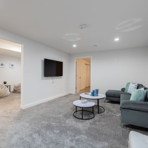 The downstairs living room features a cozy section, accent seating and a 55" smart tv to stream all your favorite content.