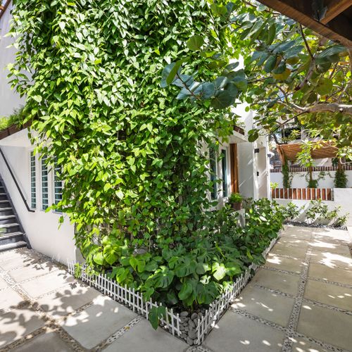 Lush green facade & charming patio create a serene oasis for relaxation.