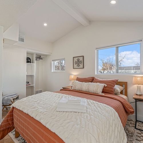 - relax in this cozy bedroom featuring a plush bed with rust and cream toned linens
- enjoy abundant natural light from two windows and charming nightstands with soft lighting
- built in shelving adds convenience with extra storage and style