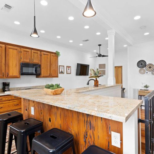 Spacious kitchen w/ a large island & warm wood cabinetry perfect for cooking together.