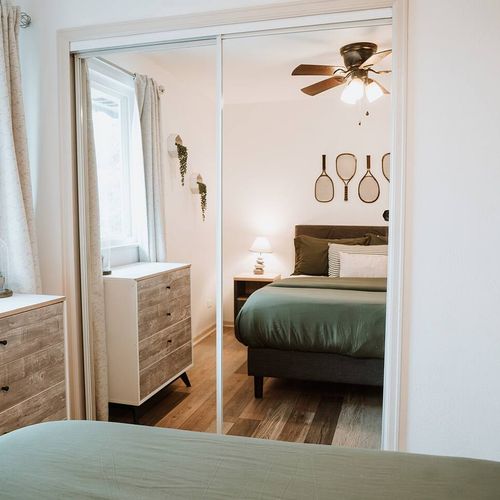 - stylish mirrored closets reflect this charming bedroom’s cozy, athletic vibe
- natural light and soft drapery create a serene mood throughout the space
- clean lines, rustic accents, and vintage tennis décor offer playful elegance