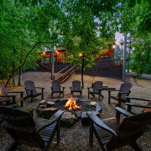 The fire pit in the back yard surrounded by Adirondack chairs.