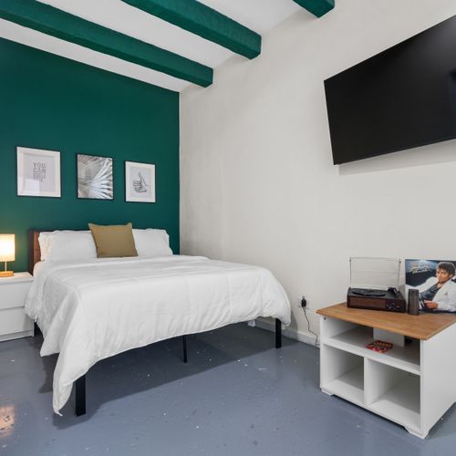 Cozy bedroom sanctuary with a soft bed, flat-screen TV, and plenty of natural light.