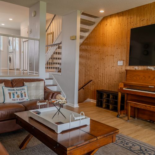 Coastal charm meets comfort with a piano, flat screen, and natural wood accents.
