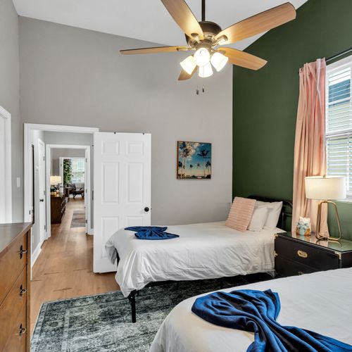 Serene bedroom w/ a bed, ceiling fan & dark green accent wall for a calm retreat.