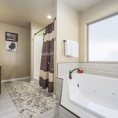 This ample bathroom offers a deep tub for relaxing and a grand mirror to enhance the space.
