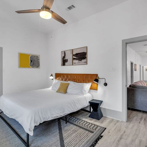 Sunlit bedroom w/ a plush bed, warm bedside lamp, & clean modern finishes.