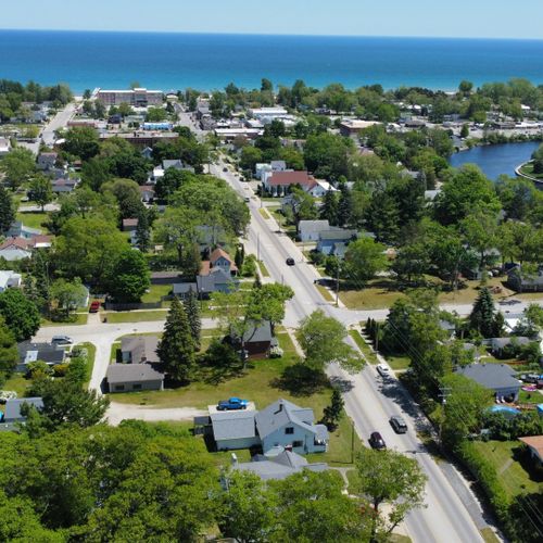 Exterior:  an aerial photo looking east with the house in the foreground and the au sable river, downtown oscoda, and lake huron in the background.