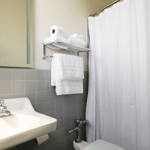Freshen up in our neat and well-maintained shower area, complete with a clean shower curtain and easy access to towels for your convenience.
