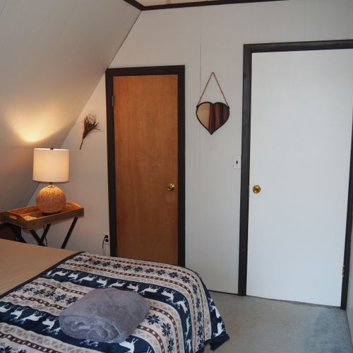 Bedroom #3 (second floor):  features a queen-size bed, walk-out balcony with lakeview, chair, nightstands with lamps, ceiling fan, and a closet.