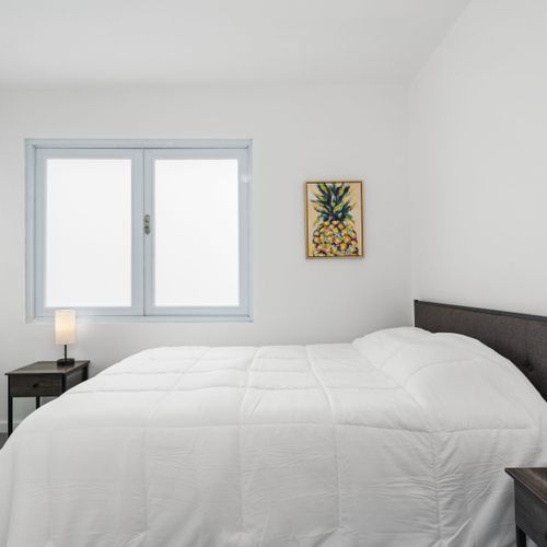 La elegancia minimalista define este dormitorio espacioso, donde la luz natural entra a través de grandes ventanales.