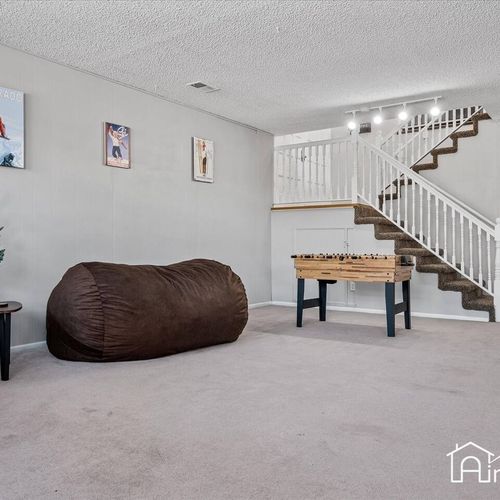 - lower level game space with foosball table, oversized bean bag, and stair access above
- playful wall art and soft carpet create a casual spot for both kids and adults to enjoy
- perfect for indoor entertainment during your cozy stay