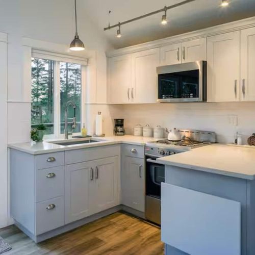 Modern kitchen with electric stovetop and oven, Blomberg stackable washer and dryer.