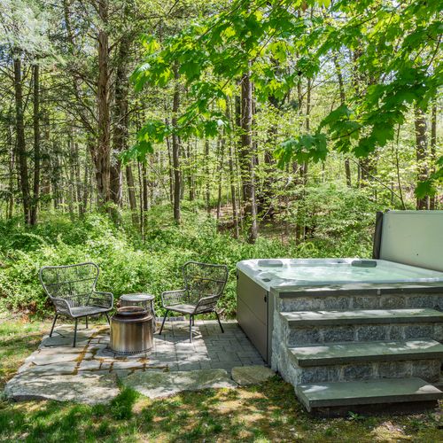 The hot tub and fire pit are perfect for cool nights, surrounded by greenery.