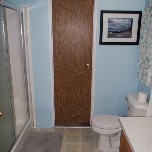 Bathroom #1:  another angle showing the combination tub / shower (on the left), the door that goes out to the laundry / mud room (in the middle of the photo), and the toilet.