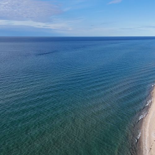 EXTERIOR:  The beach along Lake Michigan that leads up to Point Betsie at the top of the photo