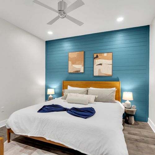 Rest easy in this stylish bedroom featuring a serene blue accent wall and contemporary decor.