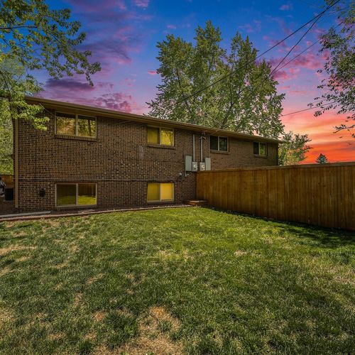 - spacious backyard framed by a privacy fence and shaded by mature trees
- brick exterior glows under a dramatic sunset sky perfect for photos
- plenty of green space to unwind play or enjoy quiet outdoor moments