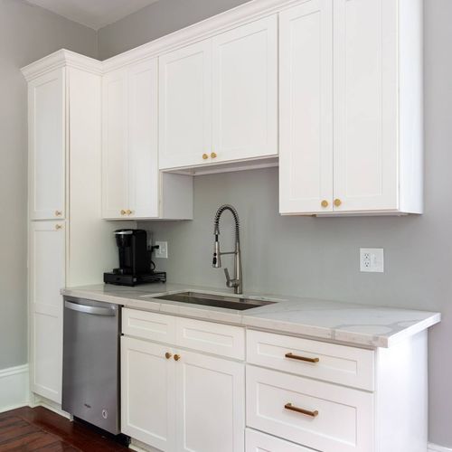 Modern and functional kitchenette featuring elegant cabinetry, brass hardware, and a deep sink for added convenience. Perfect for preparing a quick meal or enjoying a fresh cup of coffee to start your day in New Orleans.