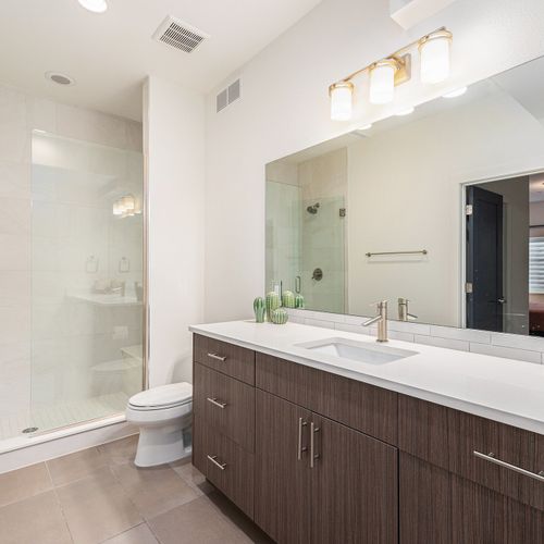 This tidy bathroom boasts a large mirror, a walk-in shower with glass doors, and a soothing atmosphere to start your day feeling fresh.