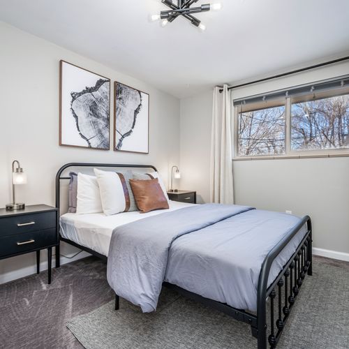 The modern and cozy upstairs queen bedroom is tastefully appointed with black out curtains.