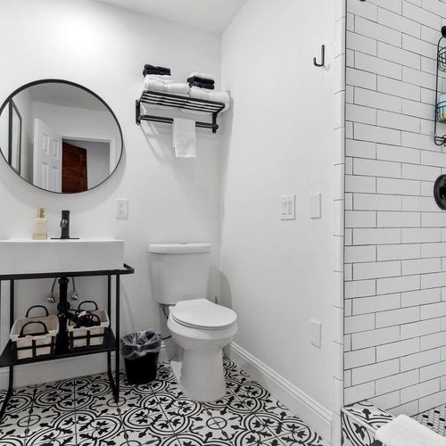 Stylish bathroom w/ a round mirror, tiled walls & a sink — fresh & modern.